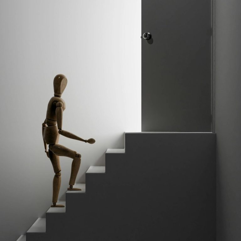 Ein Kunstfigur geht eine Treppe hinauf zu einer Tür in einem minimalistisch gestalteten Raum.