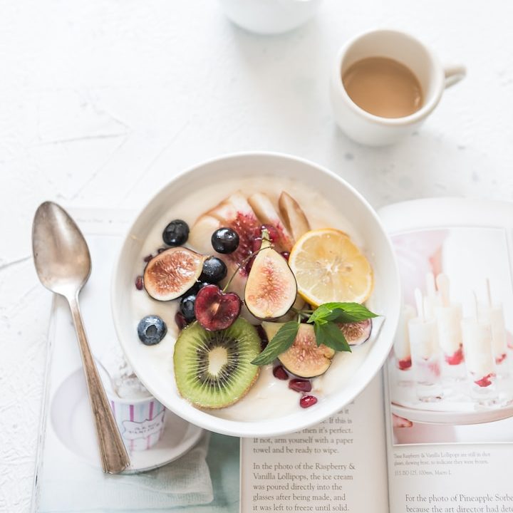 Frühstückstisch mit einer Schüssel Obst, Joghurt und einer Tasse Kaffee.