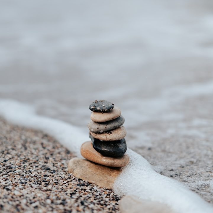 Steinhaufen am Strand, umgeben von sanften Wellen und feinem Sand.